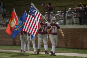 Seniors Austin Porter (98) and Noah Emert (74) lead the captains onto the field in a salute to Veterans Day. Well done.